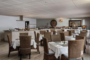 un restaurante con mesas y sillas blancas y una barra en Protea Hotel by Marriott Walvis Bay Indongo, en Walvis Bay