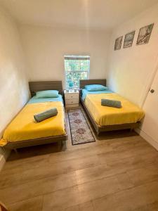 two beds in a small room with yellow sheets at Nice 2 Twin bedroom - Best central location in Miami - We have Drop off Service and Laundry for free!!!! in Miami