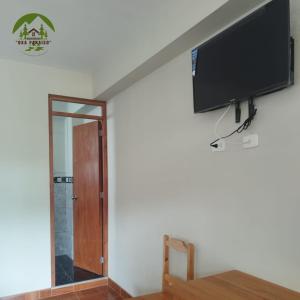 TV de pantalla plana colgada en una pared junto a una puerta en Hospedaje Oxa Paraíso, en Oxapampa