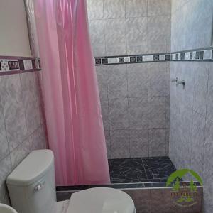 uma casa de banho com uma cortina de chuveiro rosa e um WC. em Hospedaje Oxa Paraíso em Oxapampa