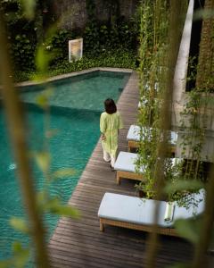 a woman walking by a swimming pool at ARTOTEL Haniman Ubud in Ubud