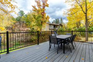 un tavolo e sedie su una terrazza con recinzione di lacbrome Chalet lake+Terrasse+BBQ+Hot-tub a Lac-Brome