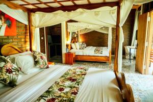 a bedroom with a canopy bed with a woman in the background at Kanchana Cottages in Uluwatu
