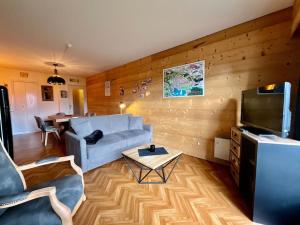 ein Wohnzimmer mit einem Sofa und einem TV in der Unterkunft Les Xettes, bel appartement style chalet avec vue in Gérardmer