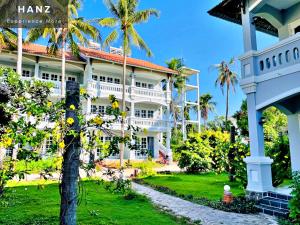 un gran edificio blanco con una palmera delante en HANZ Sun Sea Glamping & Beach Resort, en Ấp Thiện Sơn