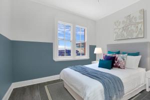 een slaapkamer met een bed met blauwe muren en ramen bij Native Rose Hotel in Sydney