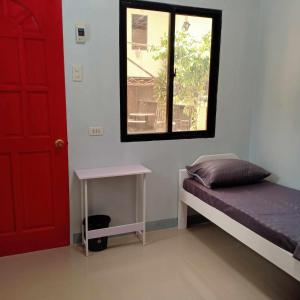 Zimmer mit einem Bett, einer roten Tür und einem Fenster in der Unterkunft JJP Dormitel in Molave