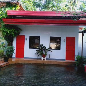 uma casa com portas vermelhas e um pátio em JJP Dormitel em Molave
