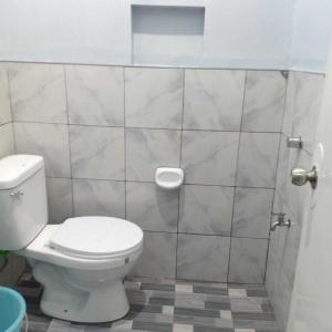 baño con aseo y pared de azulejos en JJP Dormitel en Molave