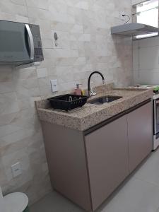 a kitchen counter with a sink and a microwave at Quitinete para temporada em Cabo Frio in Cabo Frio