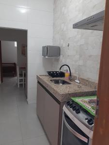 a kitchen with a sink and a stove top oven at Quitinete para temporada em Cabo Frio in Cabo Frio