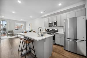 a kitchen with white cabinets and a stainless steel refrigerator at Luxurious Condo with Rooftop and Parking near University City in Philadelphia