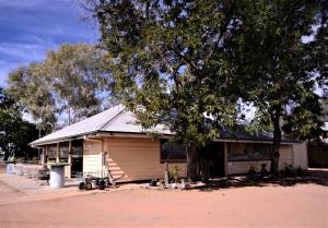 a house with a tree in front of it at Ironbark Inn in Barcaldine