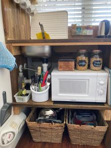 a kitchen shelf with a microwave and baskets of utensils at Gisborne Dream Suite in Gisborne