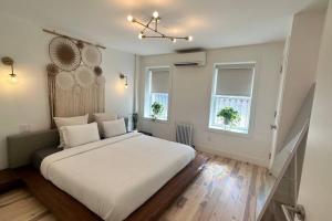 1 dormitorio con 1 cama blanca grande y 2 ventanas en Bright, airy, luxe hideaway”w” private backyard, en Brooklyn