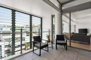 balcón con sillas, sofá y ventanas en Urban Rest Double Bay Apartments en Sídney