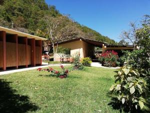 a house with a yard with flowers in front of it at Ecolodge Guancascos, cabaña para 16 personas al pie del PN Celaque in Villa Verde