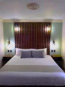 a bedroom with a large white bed with a wooden headboard at Añoranza Hotel Boutique in Ciudad Hidalgo
