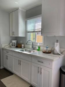 a kitchen with white cabinets and a sink and a window at Lovely 2 bedrooms with parking in Carson in Carson