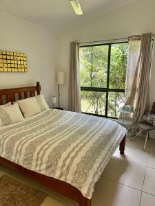a bedroom with a bed and a large window at Cairns Rainforest Retreats in Bellenden Ker
