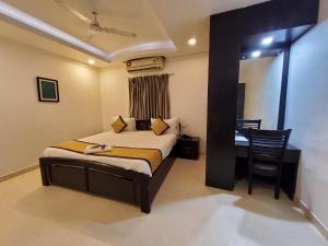 a bedroom with a bed and a table and a chair at Skyry Residency in Chennai
