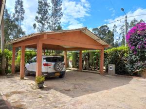 un posto auto coperto con un'auto parcheggiata in un parcheggio di "Confortable Cabaña entre Paipa y Duitama" a Duitama