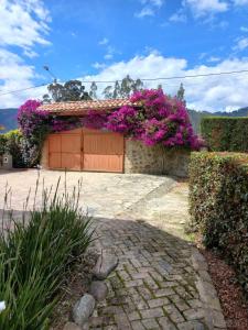 una casa con fiori viola su un lato di "Confortable Cabaña entre Paipa y Duitama" a Duitama