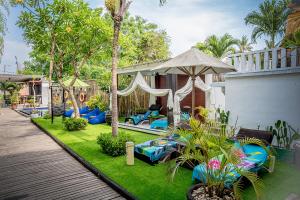 einen Garten mit Stühlen, einem Sonnenschirm und Bäumen in der Unterkunft Oasis Lembongan in Nusa Lembongan