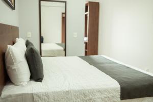 a bedroom with a bed with pillows and a mirror at Roma Hotel by H Hotéis - Airport in Brasília