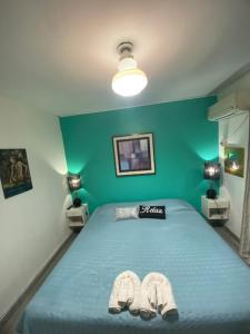 ein Schlafzimmer mit einem blauen Bett und Hausschuhen darauf in der Unterkunft Temporarios Colón - Habitación Matrimonial in Posadas