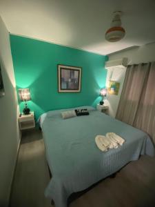 ein grünes Schlafzimmer mit einem Bett mit zwei Handtüchern darauf in der Unterkunft Temporarios Colón - Habitación Matrimonial in Posadas