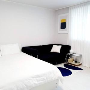 a white bedroom with a large bed and a couch at Stay Daewha Kintex 5min Daewha Station 5min Baek Hospital 1min in Goyang