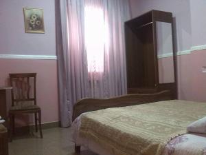 um quarto com uma cama, uma janela e uma cadeira em Hostel Georgia em Kutaisi