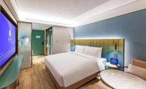 a bedroom with a large white bed and a tv at Man Xin Zhangjiagang Pedestrian Street Hotel in Zhangjiagang