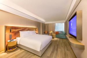 um quarto de hotel com uma cama e uma televisão em Man Xin Zhangjiagang Pedestrian Street Hotel em Zhangjiagang