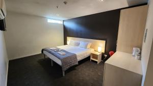 Nomads Queenstown Hostel في كوينزتاون: غرفة الفندق بسرير وطاولة