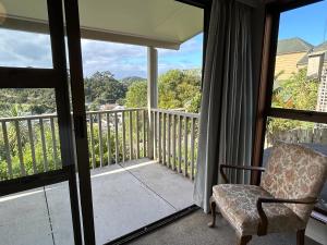 a room with a balcony with a chair and a window at High Tides in Ngunguru