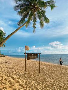 a sign on a beach with a palm tree at Thanh Kieu Beach Resort in Phu Quoc