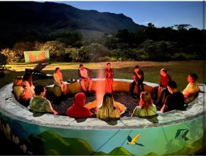 um grupo de pessoas sentadas em torno de uma fogueira em Pousada Morro da Baleia em Alto Paraíso de Goiás