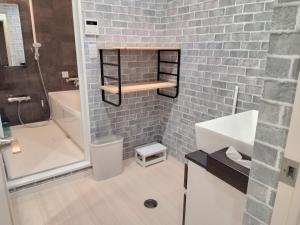 bagno con lavandino bianco e parete in mattoni di ヴィラ砂時計九十九里超豪華大型貸切別荘寝室五つペット可サウナ本格カラオケグランドピアノ麻雀 a Kujukuri