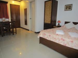 1 dormitorio con cama, mesa y comedor en Residencia Lourdes, en Mactan