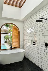Un baño blanco con bañera y ventana. en Two- bedroom Luxury Villas, en Uluwatu 39 fotos más