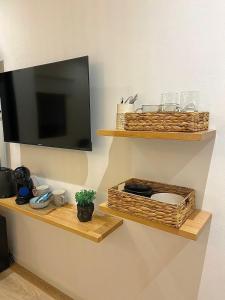 a flat screen tv on a wall with two wooden shelves at Magnolia Suites in Nono