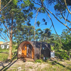 een klein houten huis in een veld met bomen bij Aldeia Ananda Imbituba in Imbituba