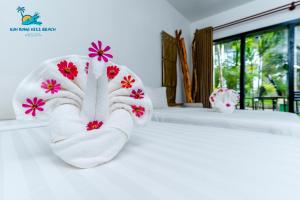 Un par de toallas blancas con flores en la cama. en Koh Rong Hill Beach Resort, en Koh Rong