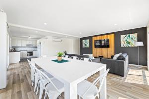 a dining room and living room with a white table and chairs at Tween Waters Merimbula in Merimbula