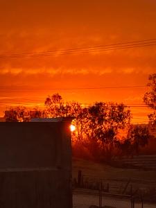 um pôr-do-sol sobre um campo com um edifício e árvores em Cozy Apartment Villas em Rosarito