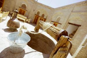 um balde de água sentado numa mesa em frente a um edifício em Karavansaray Xurjin Old em Bukhara