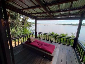 a bed on a deck with a view of a river at Pomelo Restaurant and Guesthouse's Fishermen Bungalow & A Tammarine Bungalow River Front in Ban Khon