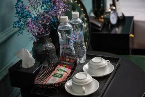 a table with two bottles of water and a tray with plates and cups at Madelise Adora Hotel & Travel in Hanoi